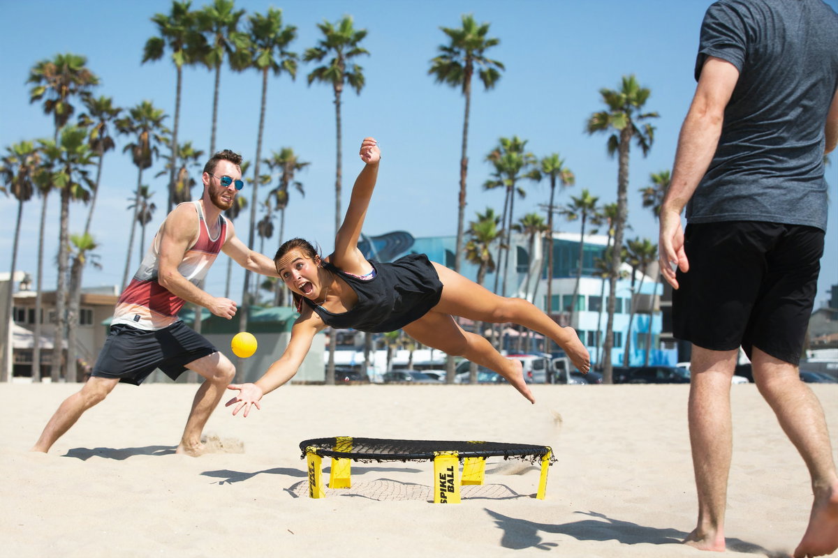 Menschen spielen am Strand Spikeball