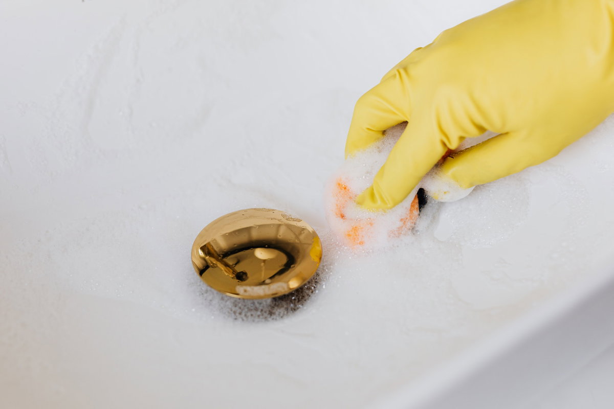 Mit Handschuhen das Waschbecken putzen