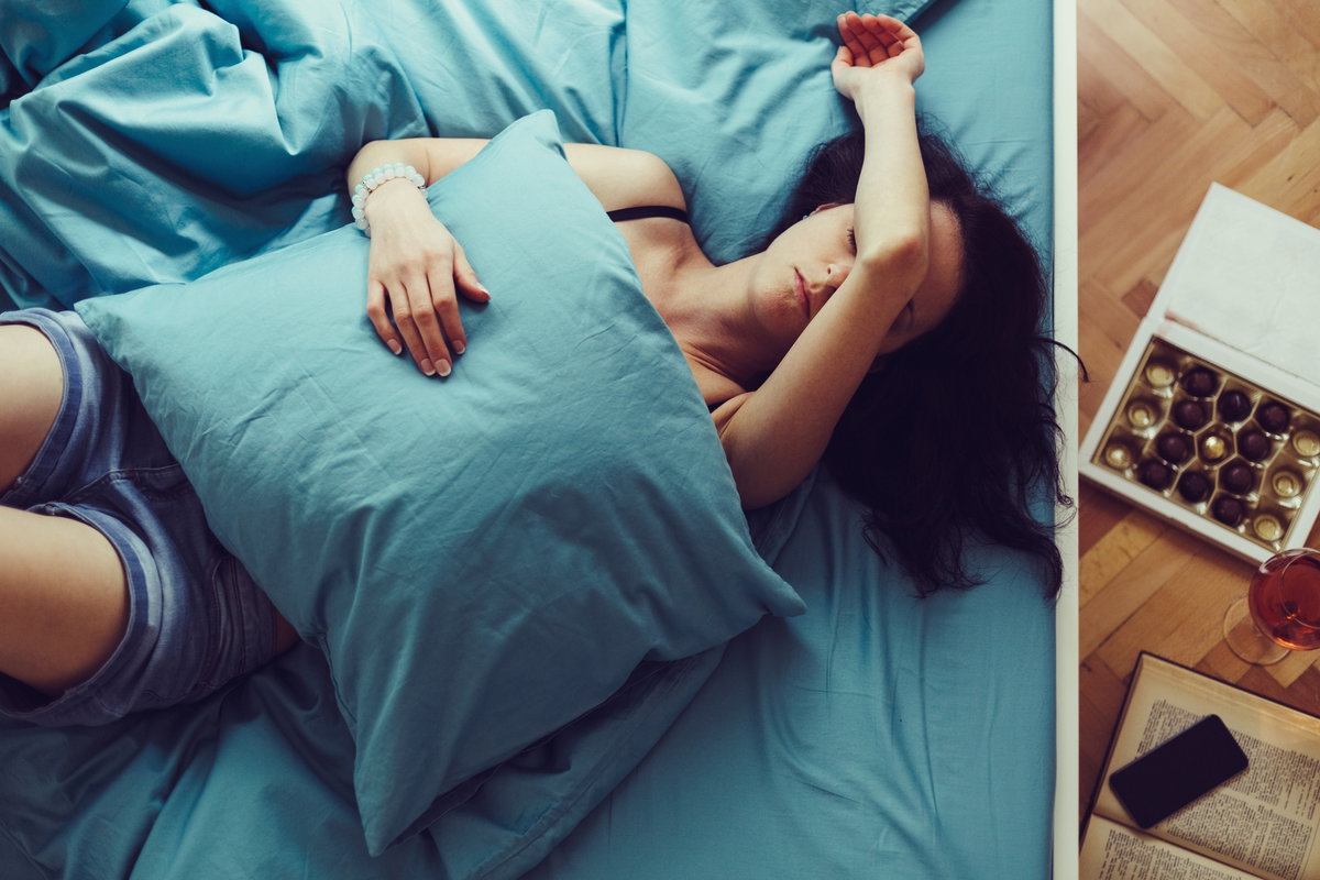Frau liegt im Bett mit Kopfschmerzen