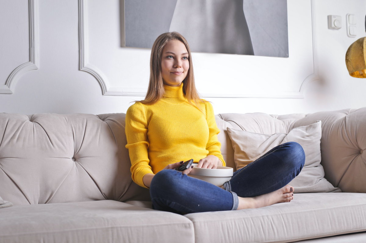 Frau sitzt auf Sofa und schaut Fernsehen.