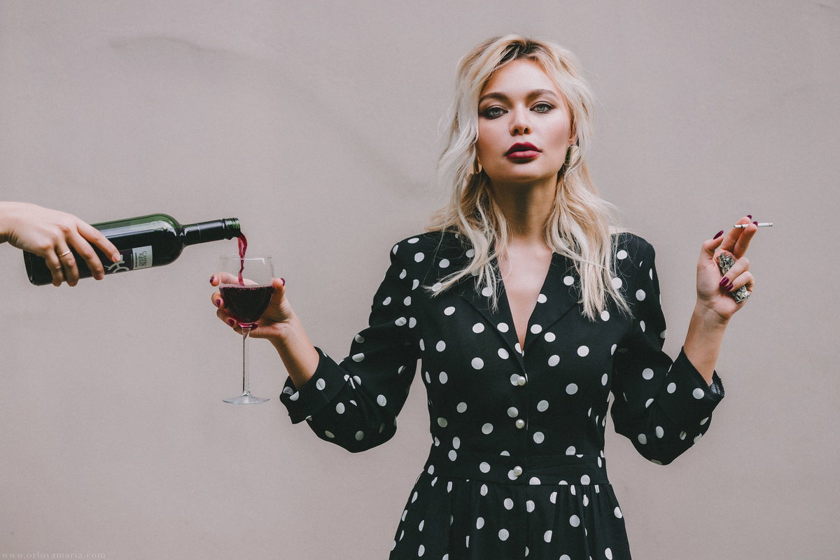 Frau mit Glas Rotwein und Zigarette in der Hand