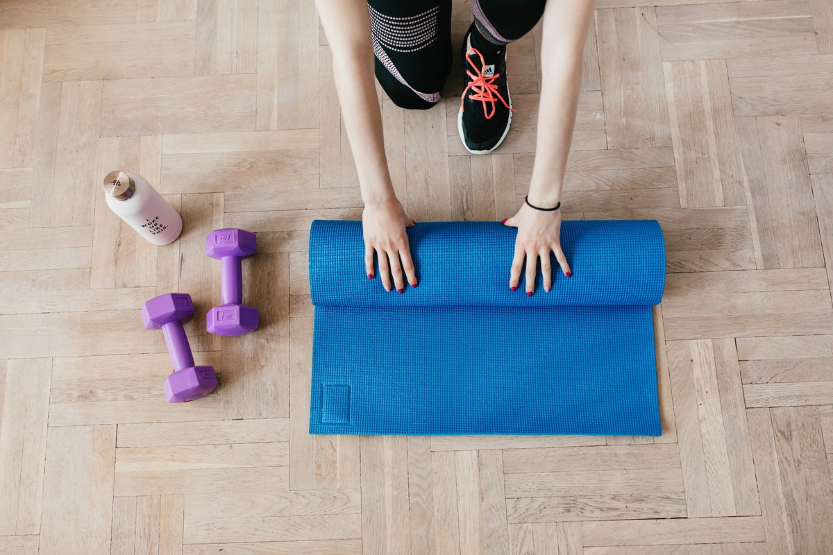 Frau rollt ihre Yogamatte zusammen