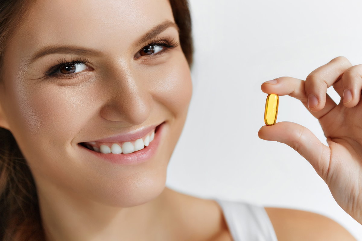 Frau hält Vitamin-Tablette in der Hand