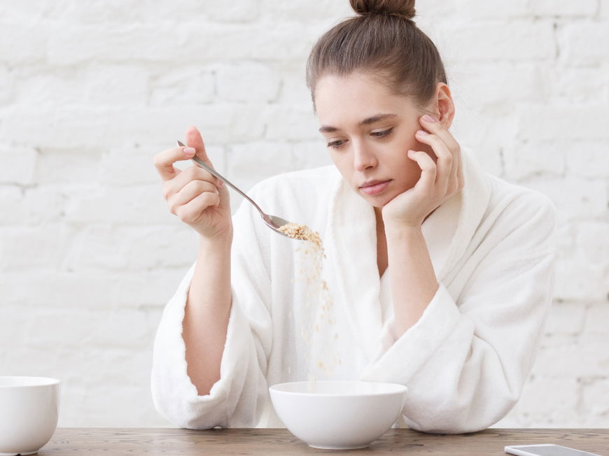 Frau schaut appetitlos auf ihr Müsli