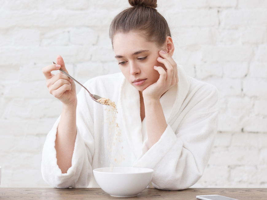 Frau schaut appetitlos auf ihr Müsli