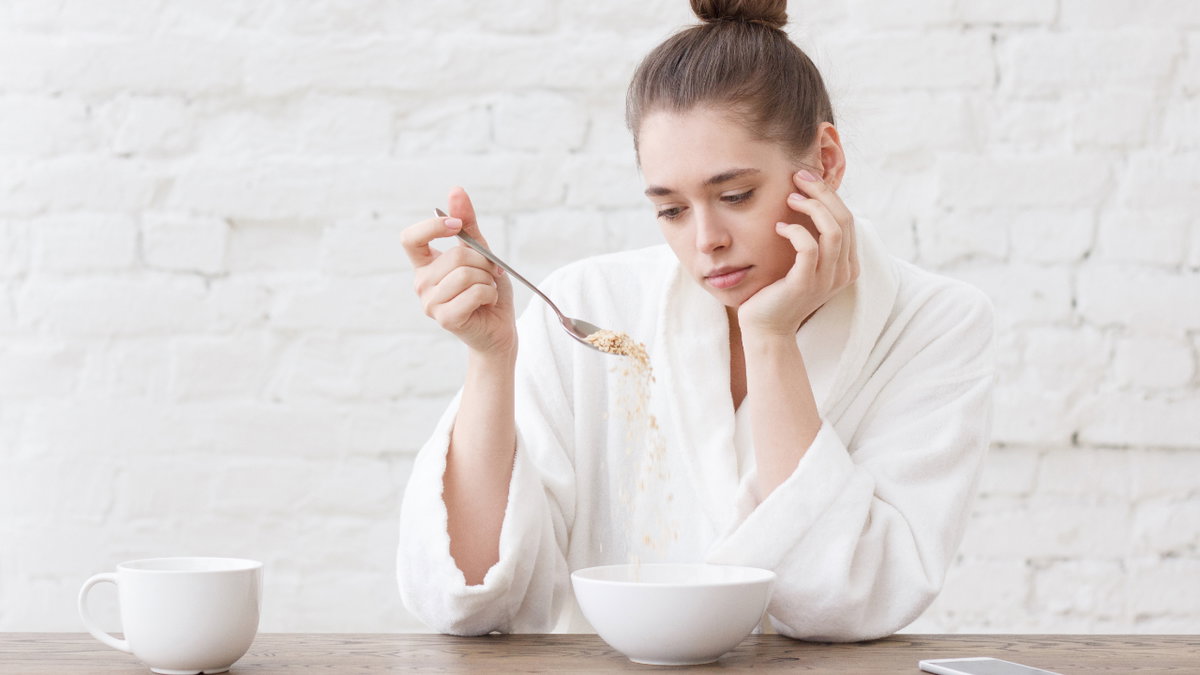 Frau schaut appetitlos auf ihr Müsli