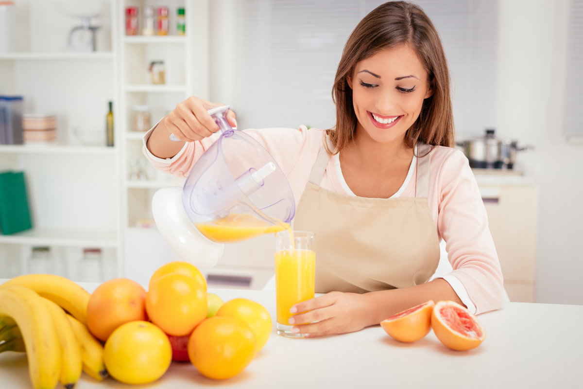 Frau gießt Orangensaft ins Glas
