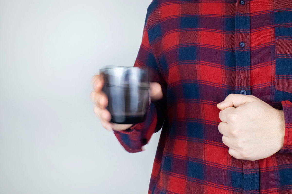 Person hält Glas in zitternder Hand