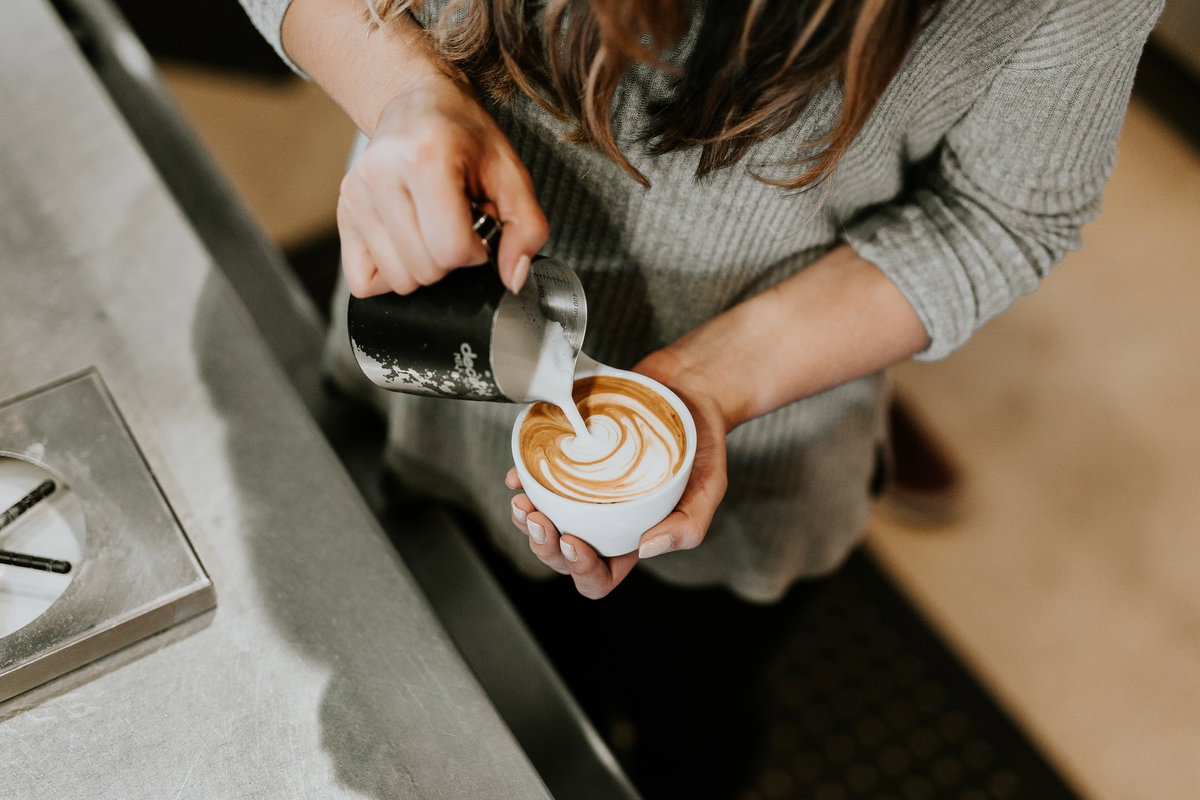 Frau bereitet Milchkaffee zu
