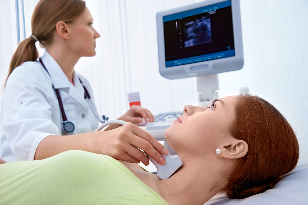 Ärztin untersucht die Schilddrüse einer Frau mittels Ultraschall