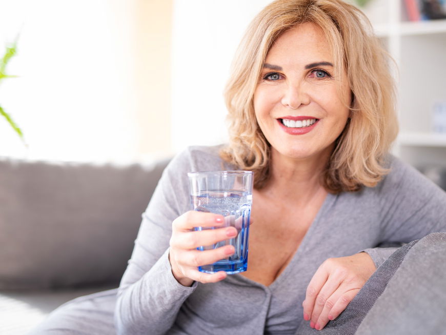 Lächelnde Frau mit Wasserglas in der Hand