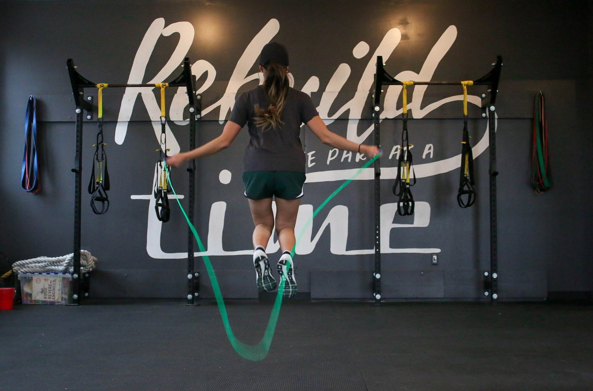 Frau beim Springseilspringen mit grünem Seil im Gym