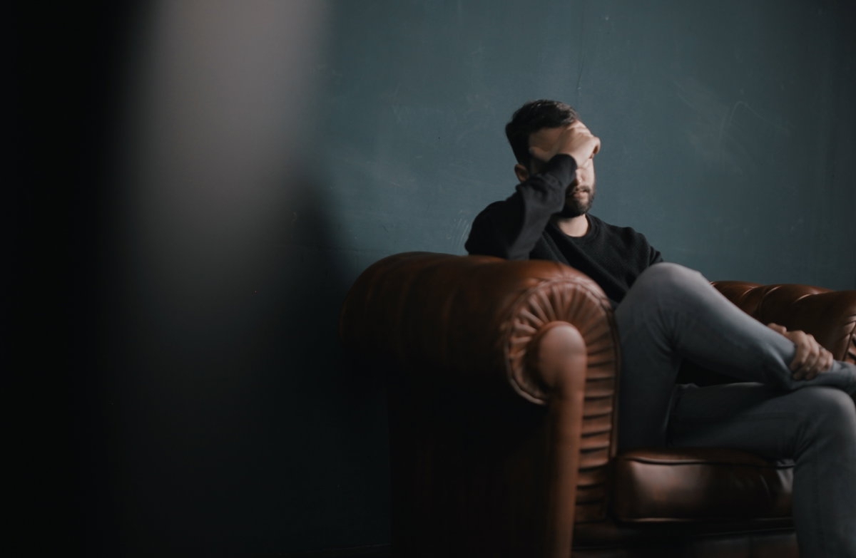 Mann mit Depressionen sitzt betrübt in Sessel