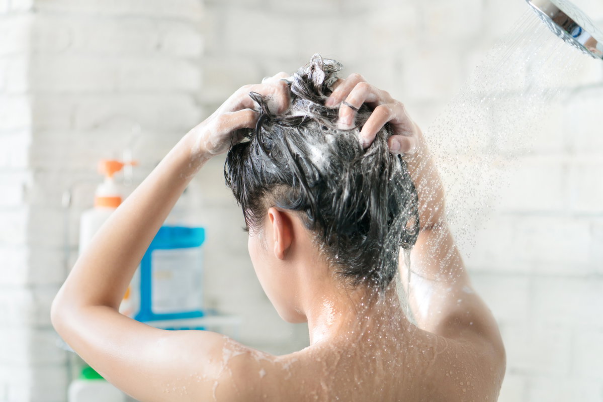 Frau wäscht ihre Haare mit Shampoo