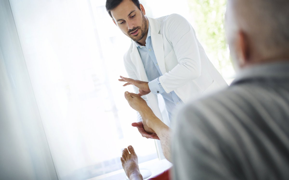 Arzt untersucht Fuß eines Patienten