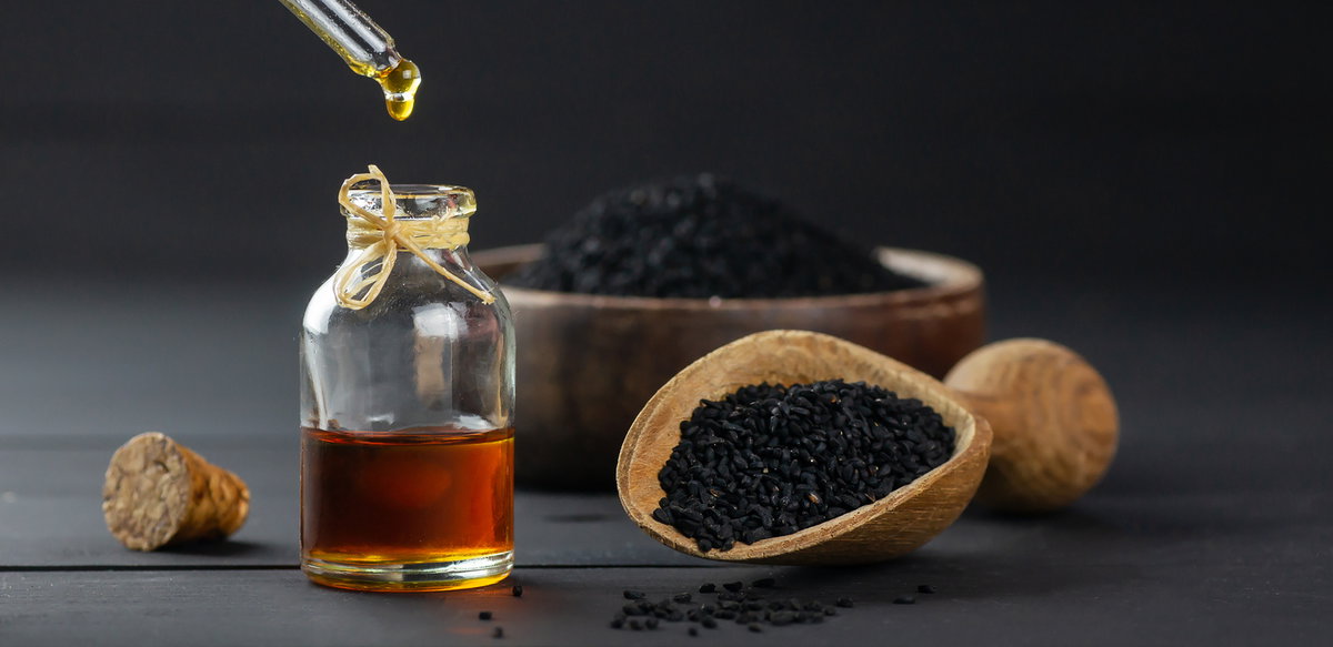Schwarzkümmelöl und Schwarzkümmelsamen auf schwarzem Tisch