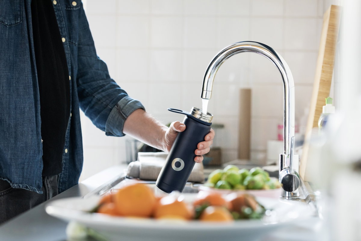 Mann füllt Leitungswasser in wiederverwendbare Flasche