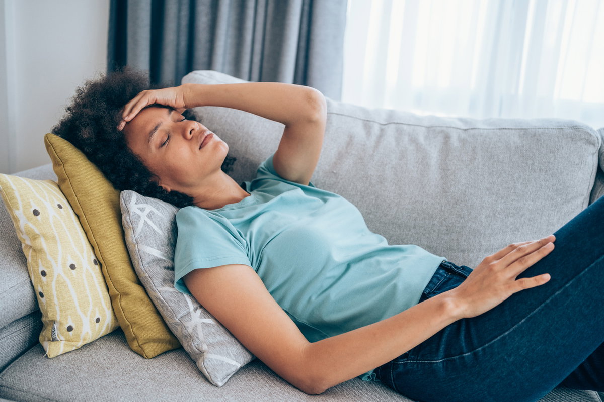 Frau mit Schwindel liegt auf Couch