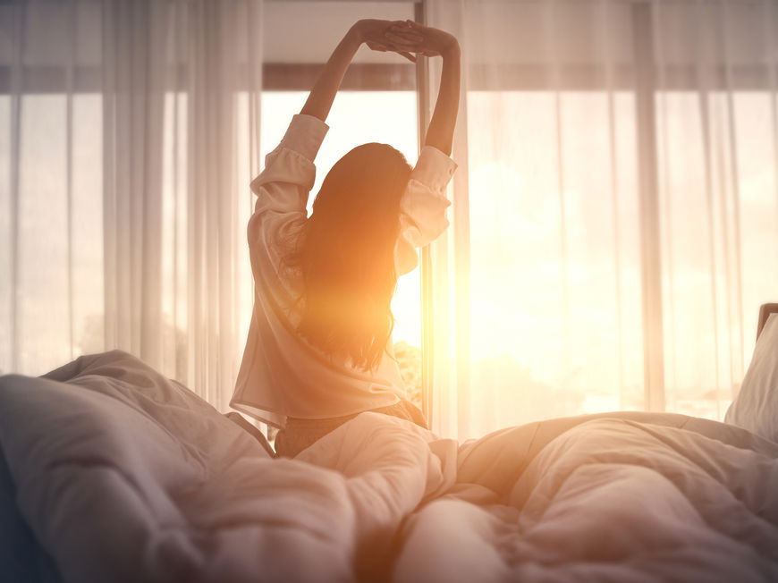 Frau steht erholt und putzmunter früh am Morgen auf