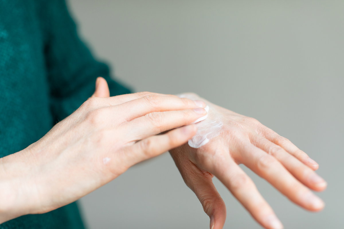Frau trägt Creme auf Handrücken auf