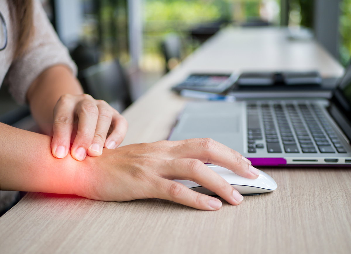 Frau im Büro mit Schmerz im Handgelenk