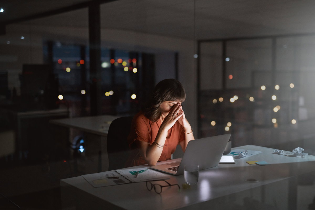 Gestresste Frau, die nachts im Büro arbeitet