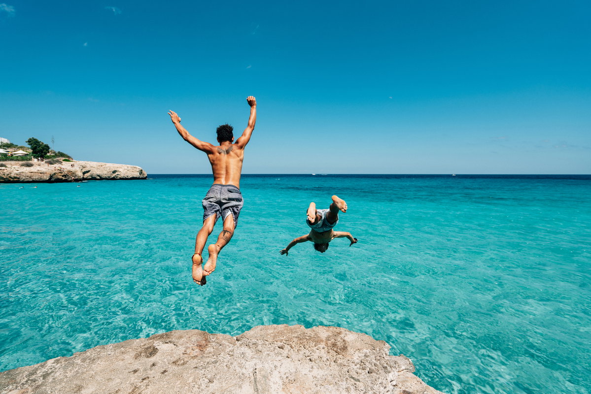 zwei junge Männer springen ins Meer