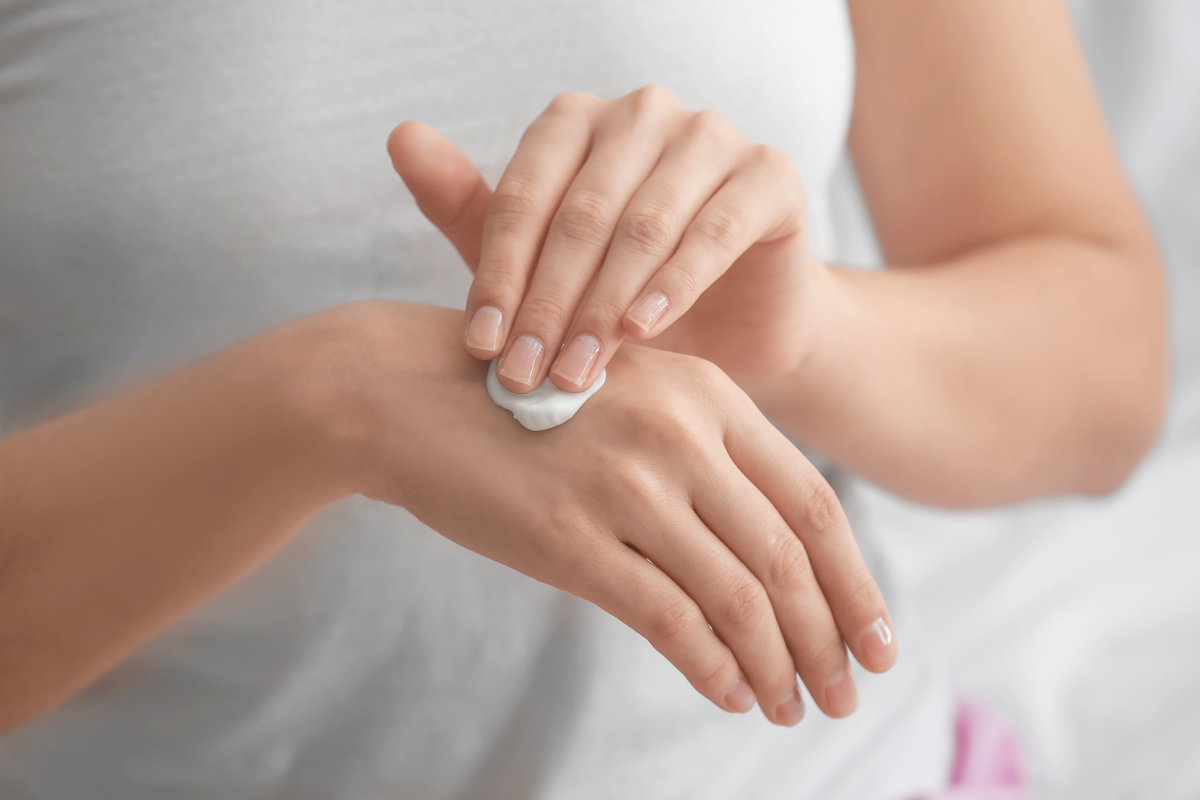 F>rau trägt Handlotion auf
