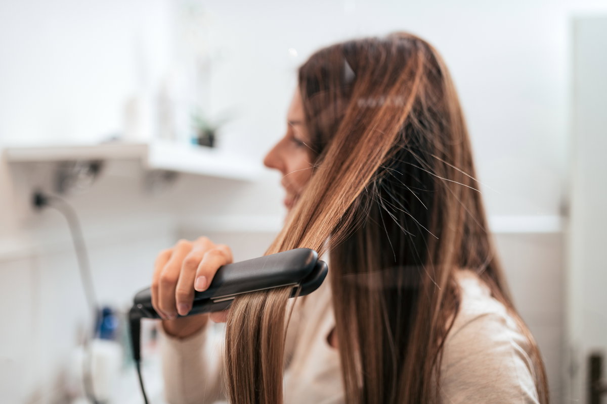 Frau glättet sich die Haare