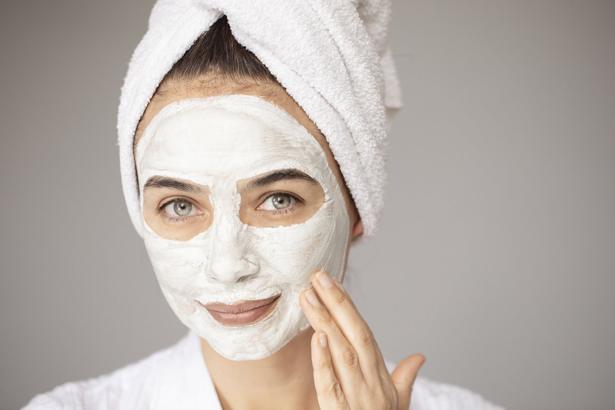 junge Frau trägt Creme-Maske auf Gesicht auf