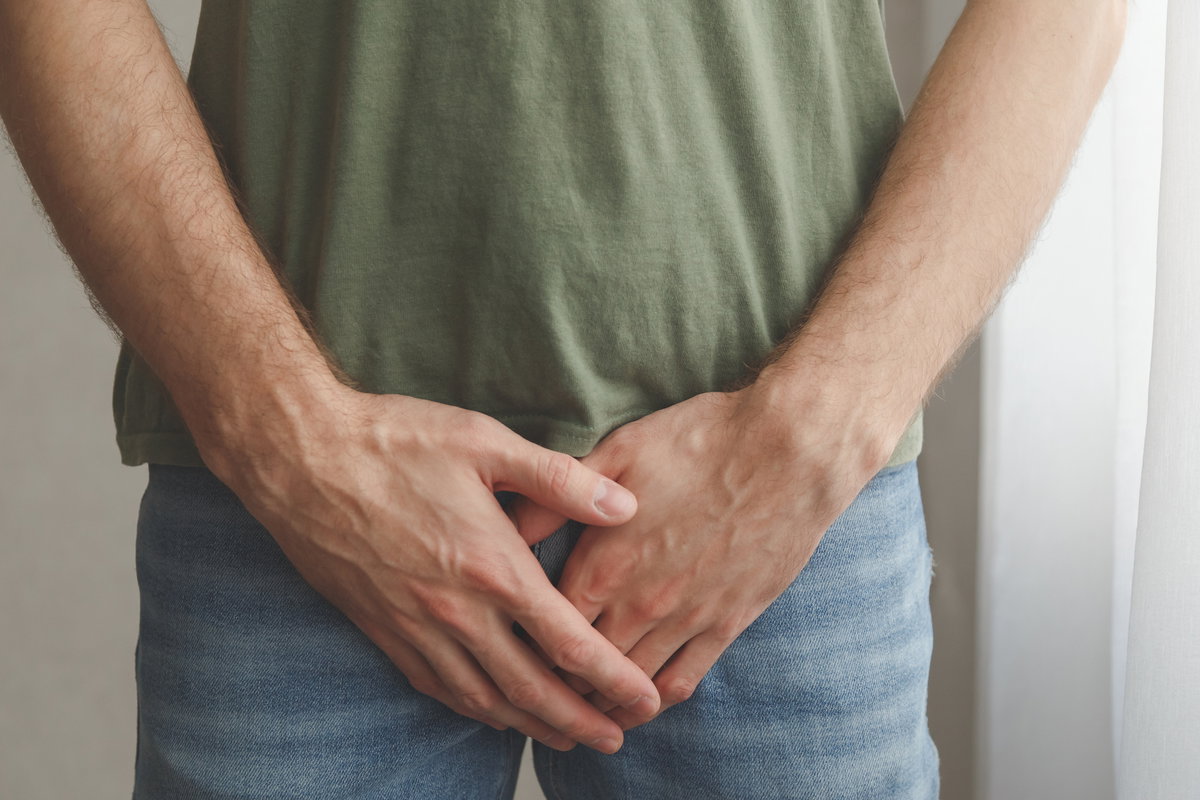 Mann hält Hand vor Schritt