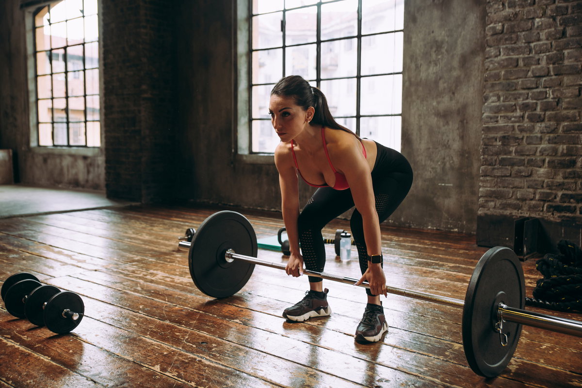 Frau beim Set-up für Deadlifts mit Langhantel