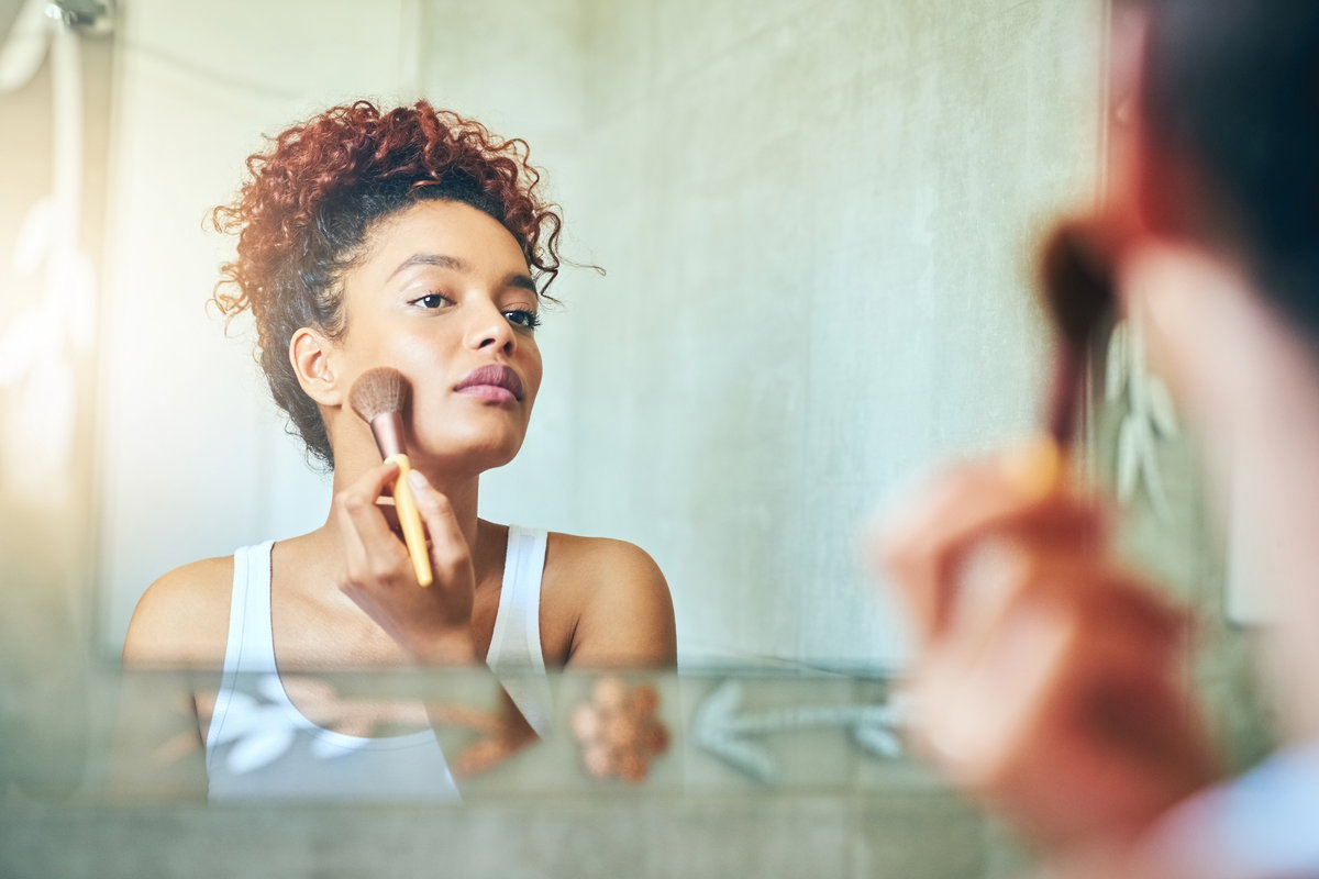 Frau trägt Make-up mit Pinsel auf