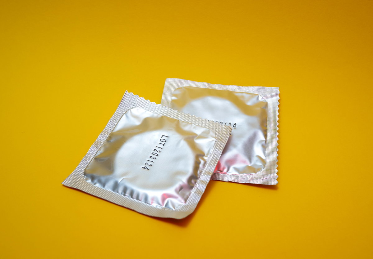 Zwei Kondome in Verpackung vor gelbem Hintergrund