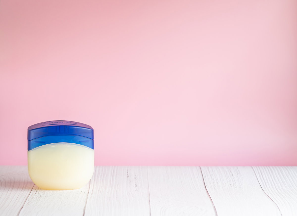 Tigel Vaseline auf Tisch vor pinker Wand