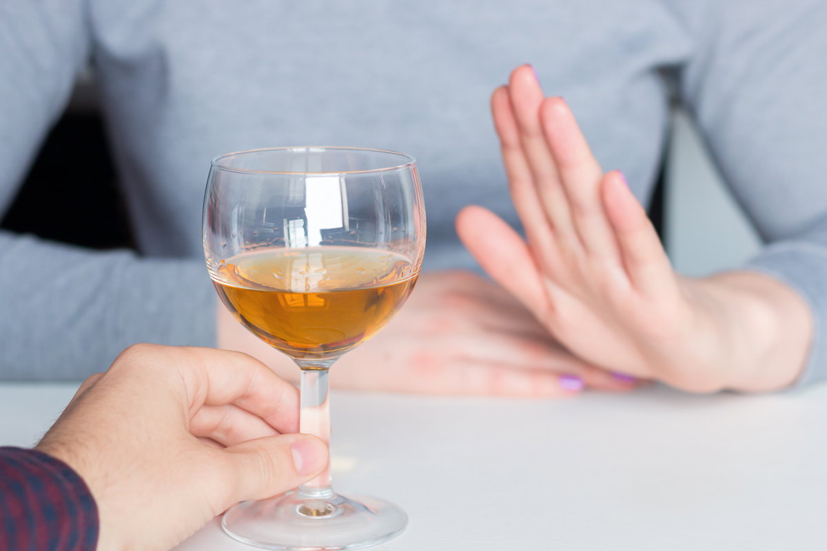 Frau lehnt mit Handgeste ein Glas Wein ab
