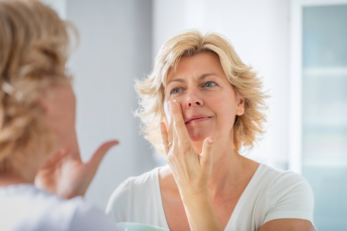 Frau cremt Gesicht ein
