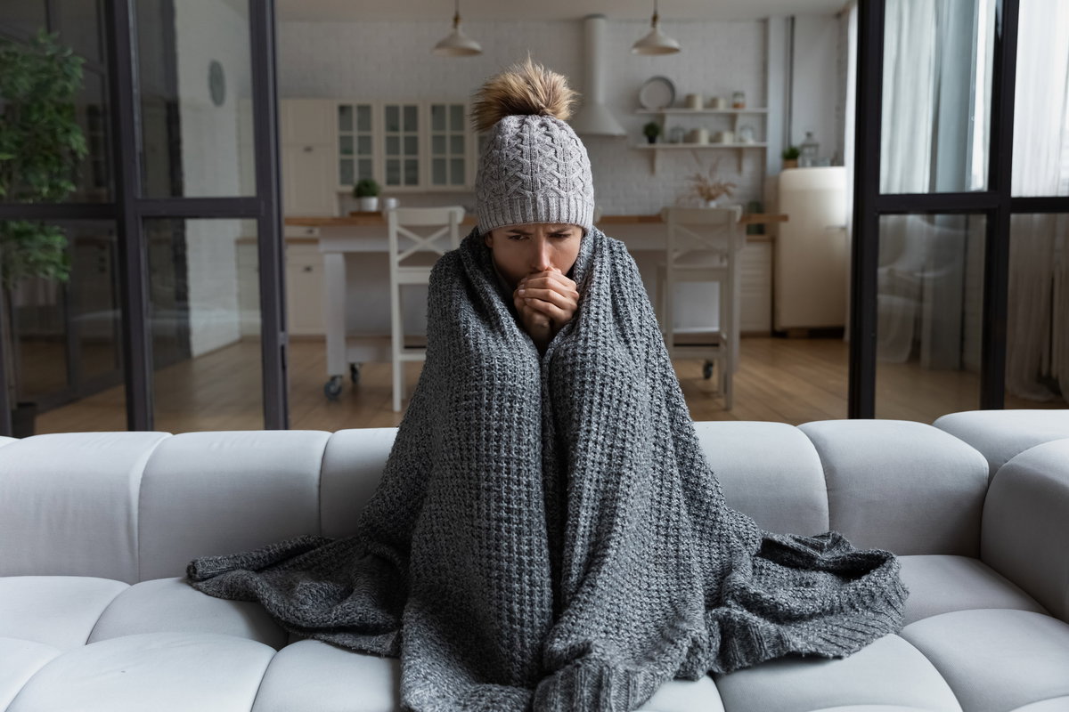 Frau mit Decke in kalter Wohnung.