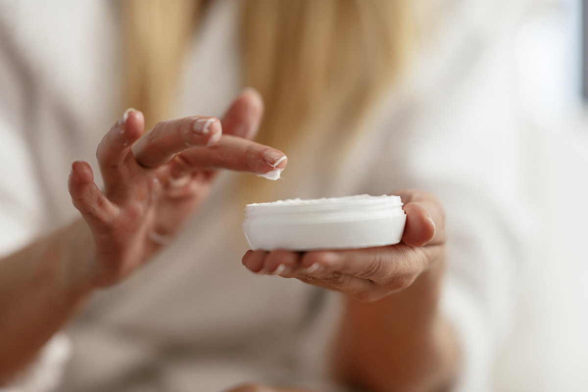Frau nimmt Creme aus Tigel