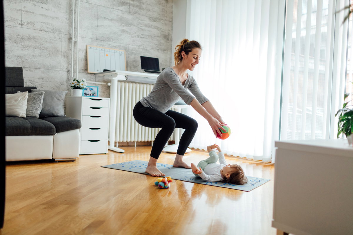Mutter macht Kniebeuge beim Spielen mit Kind