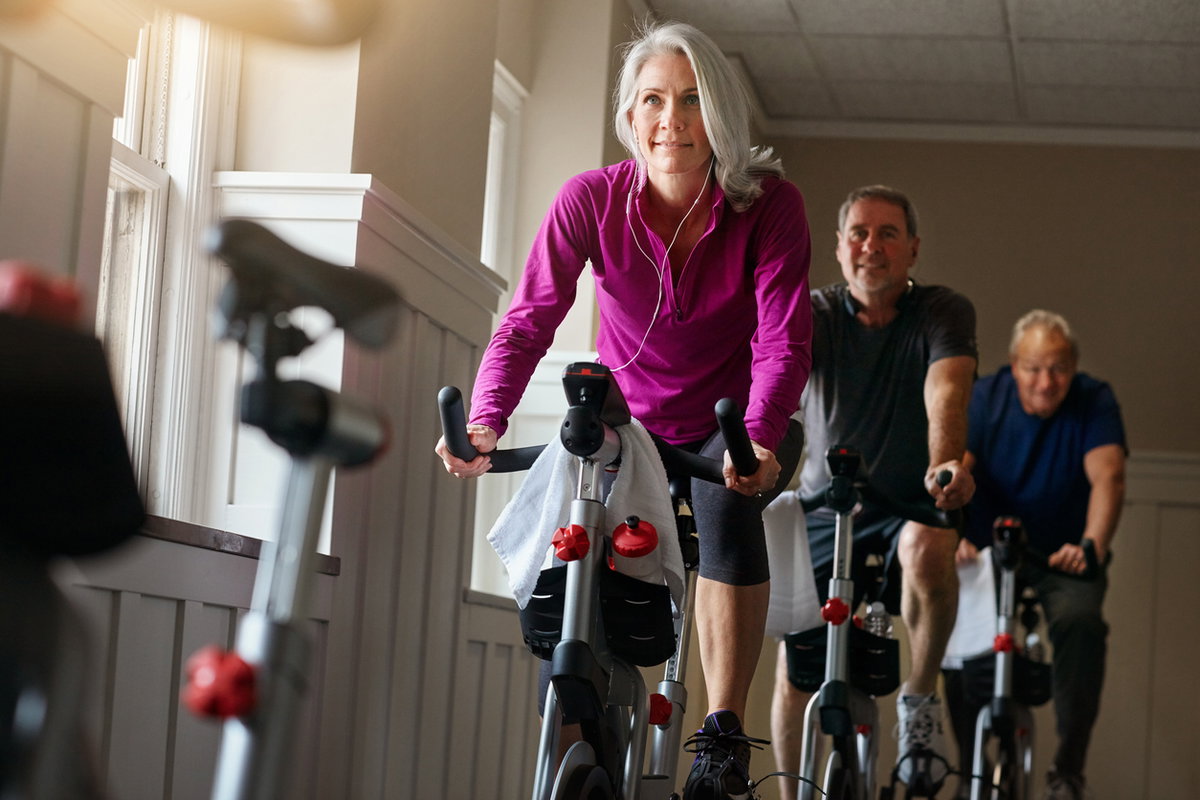 Frau mit grauen Haaren nimmt an Spinning-Kurs teil