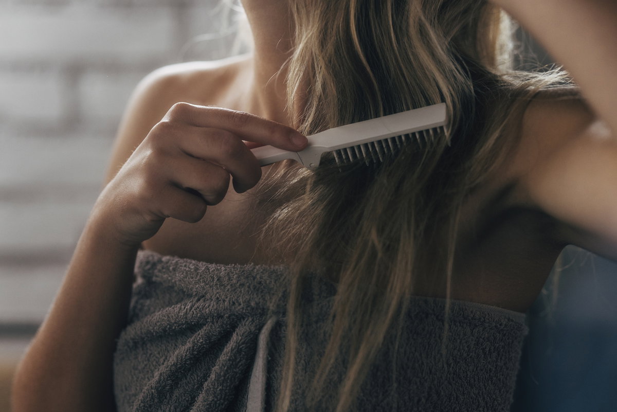 Frau kämmt sich Haare nach der Dusche