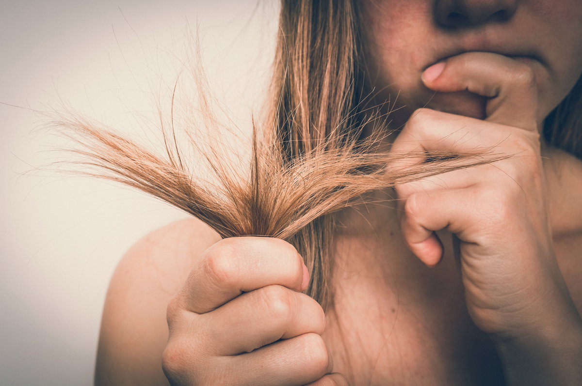 Frau prüft ihre Haarspitzen mit kritischem Blick