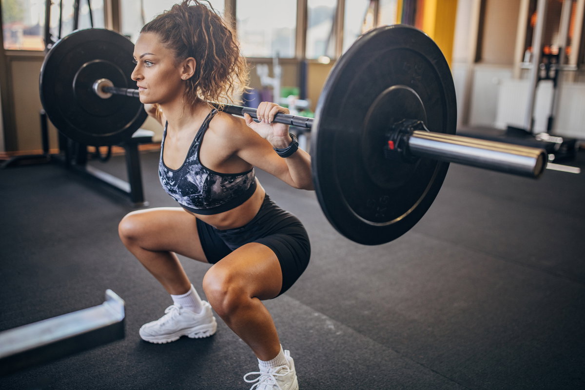 Frau mit Langhantel macht Squats