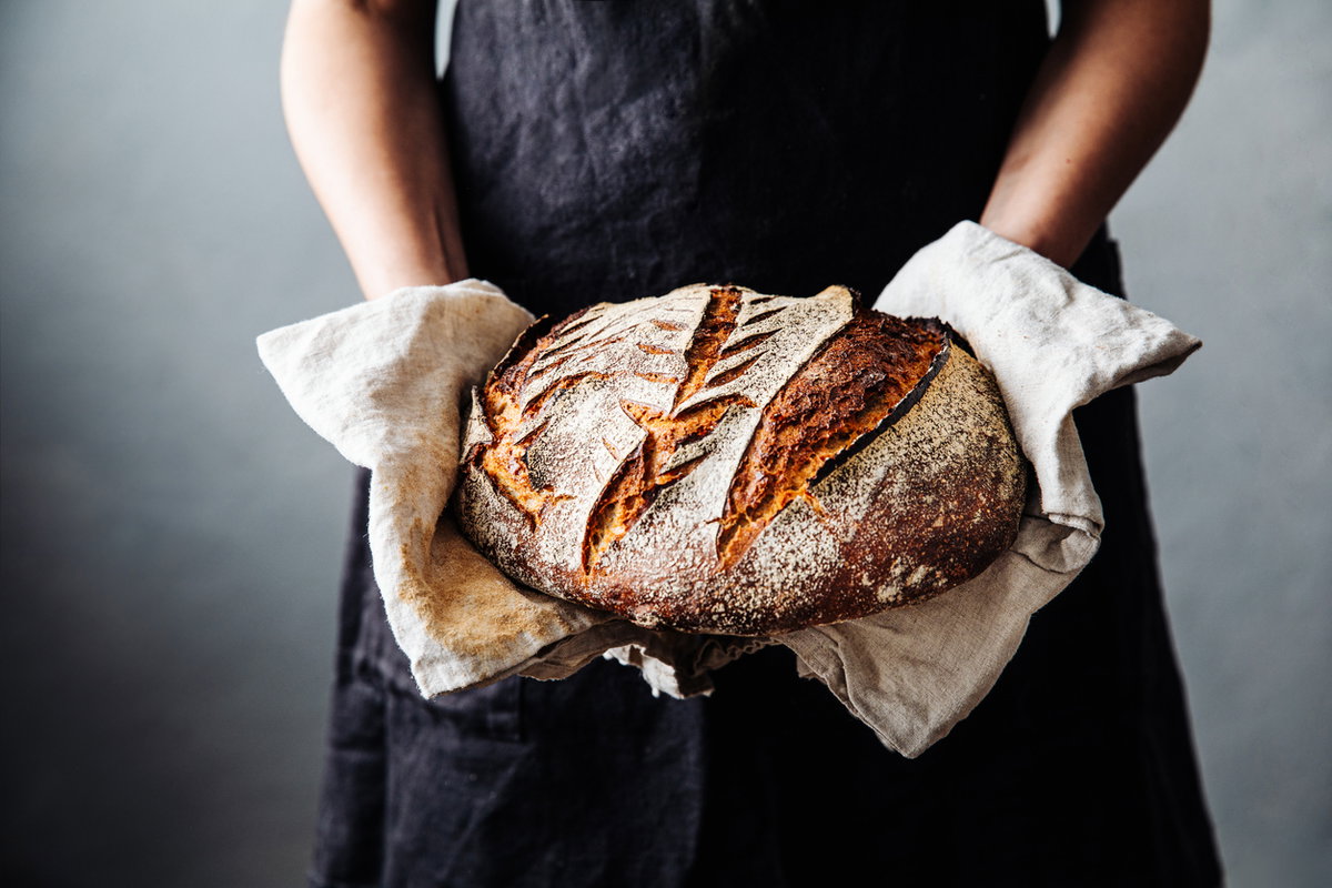 Bäckerin hält frisches Sauerteigbrot in den Händen