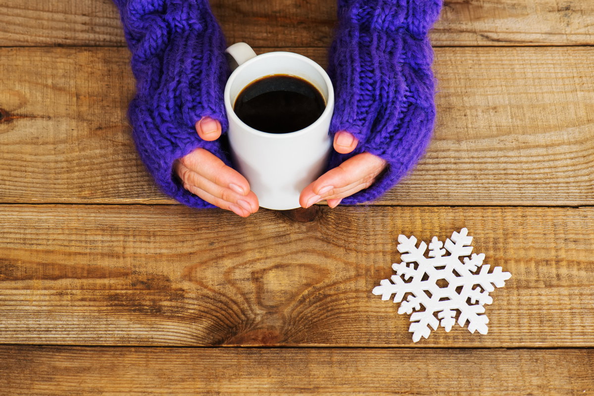 Frau wärmt Hände an einer Tasse Kaffee
