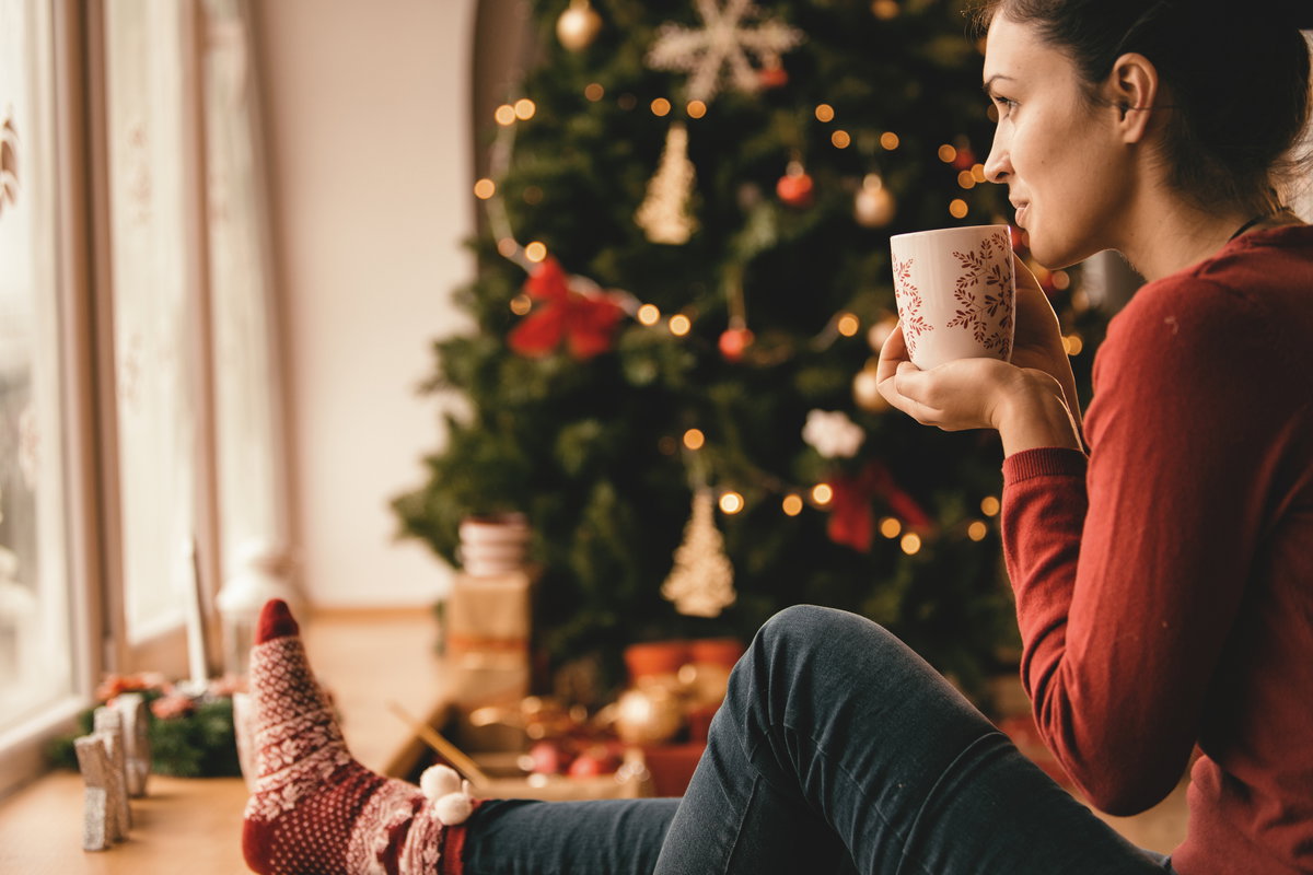Frau mit Tee unter Weihnachtsbaum