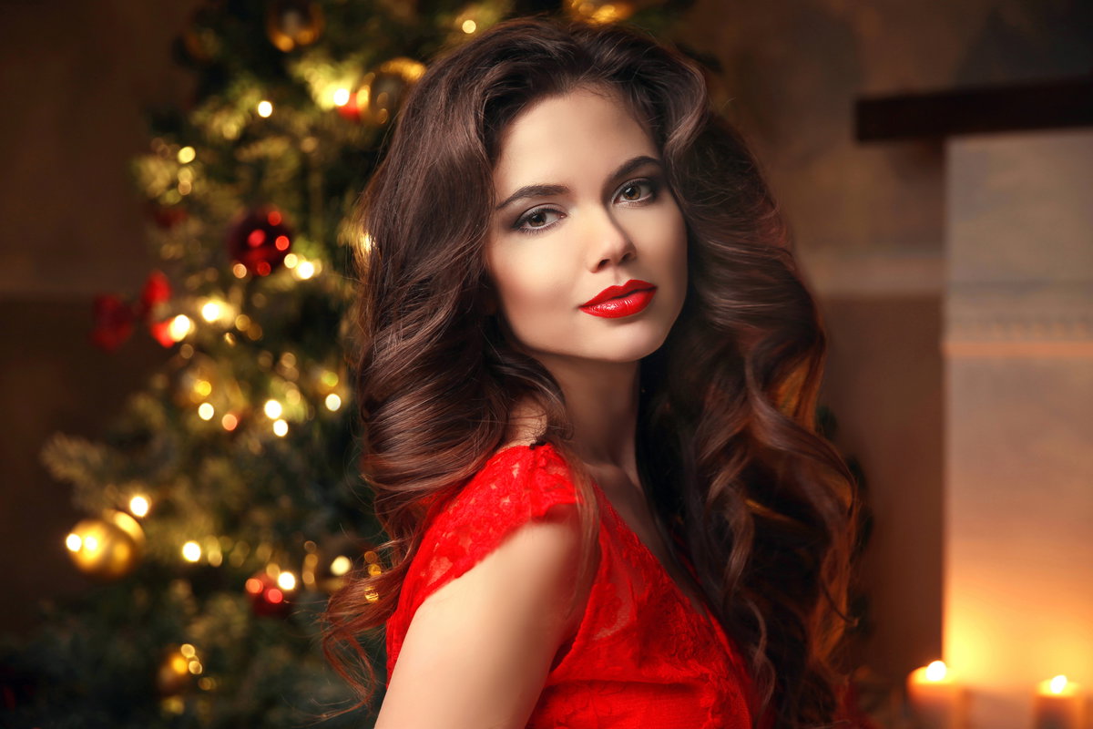 Frau mit roten Lippen vor Weihnachtsbaum