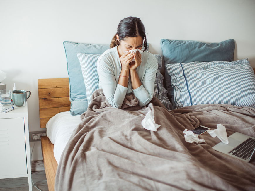 Frau liegt mit Erkältung im Bett