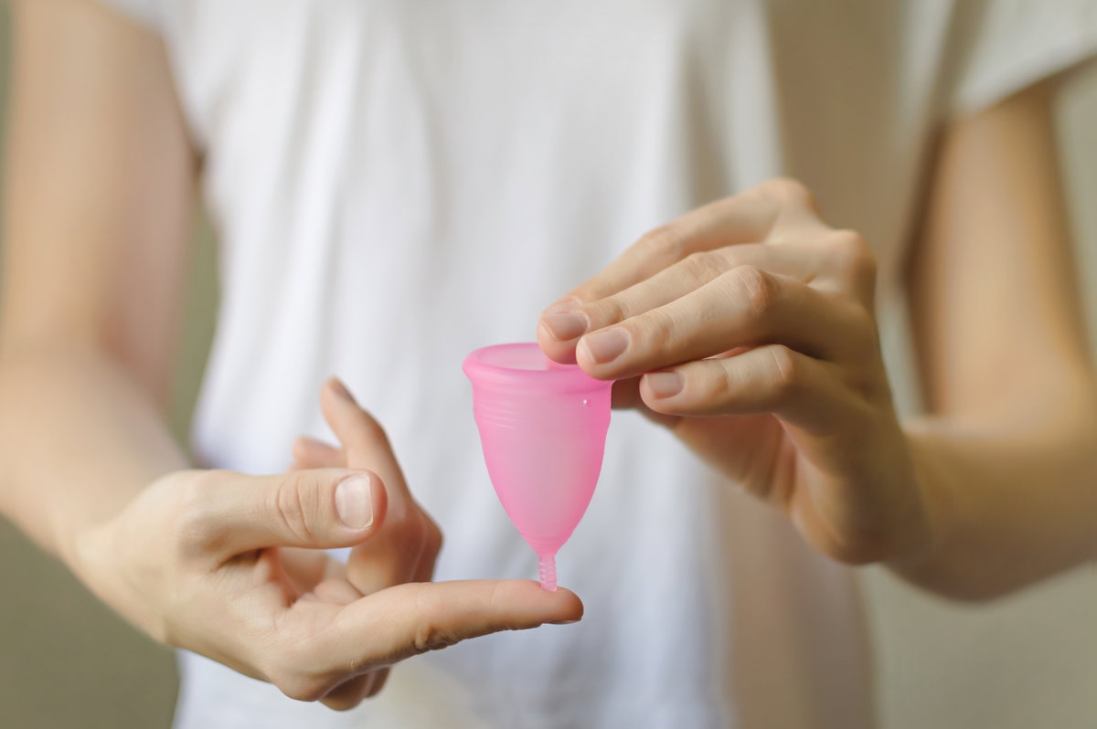 Frau hält Menstruationstasse in den Händen